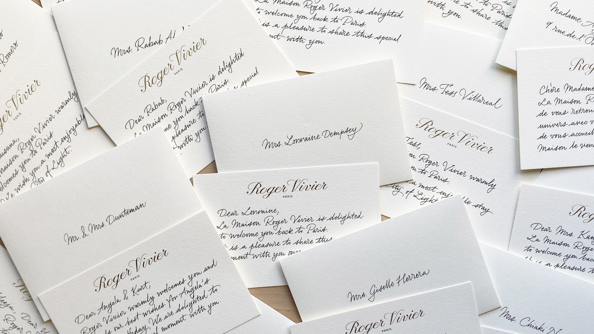 Scattered handwritten invitation cards with elegant cursive text on a white background