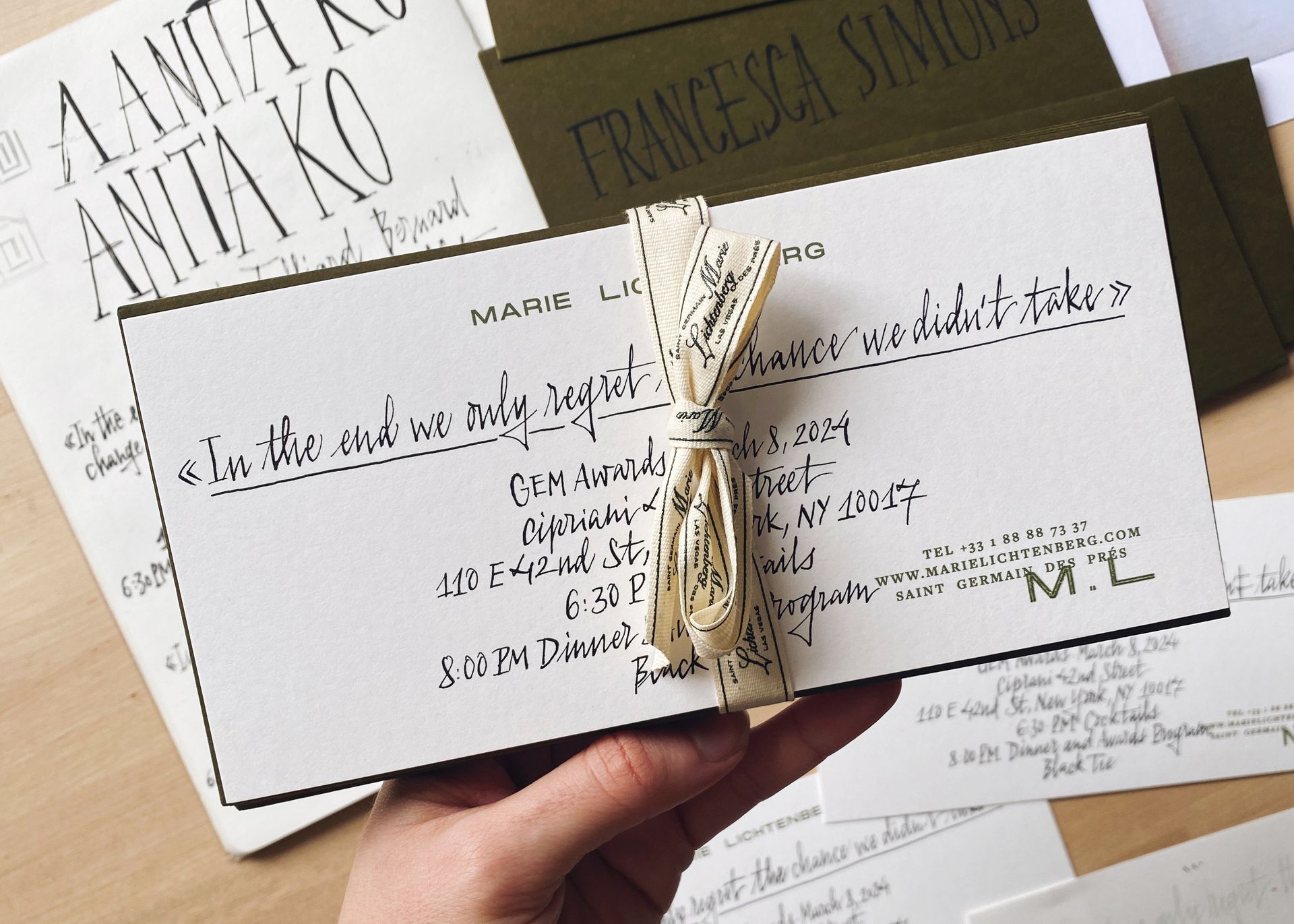 Hand holding a stack of elegant wedding invitation cards tied with twine.