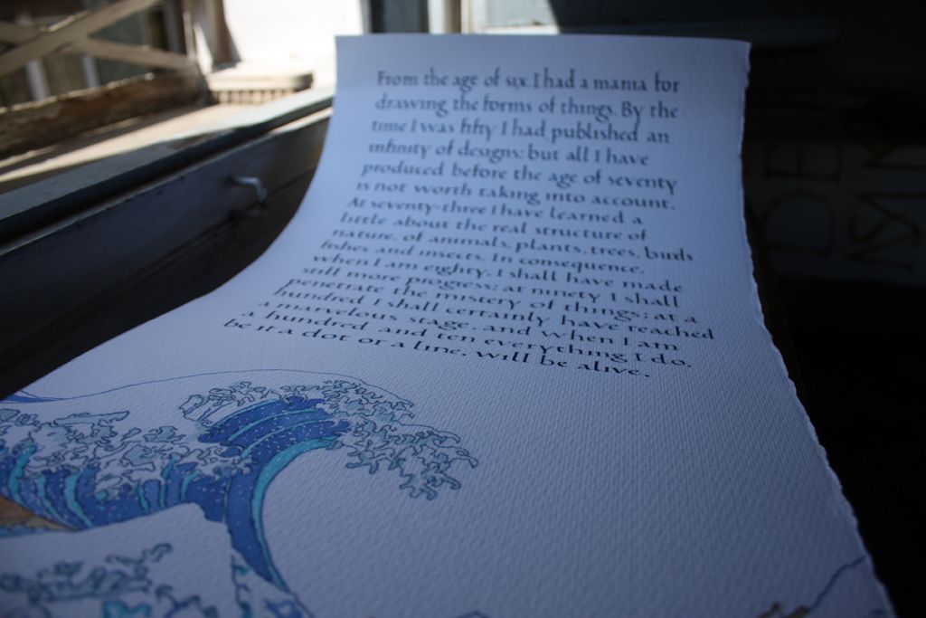 Close-up of a curled printed page with dark text and a blue wave illustration on a blue surface.