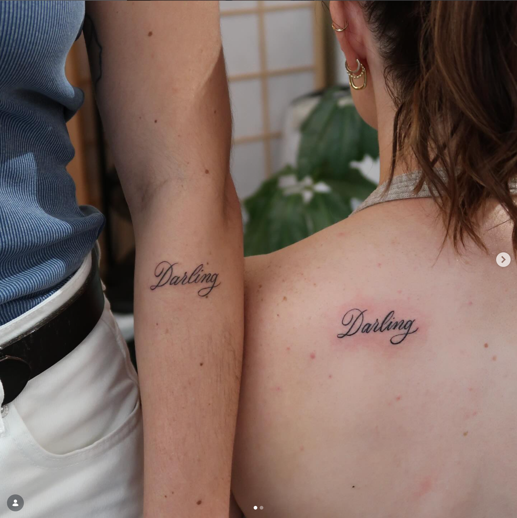 Two people showing matching “Darling” script tattoos on arm and shoulder.