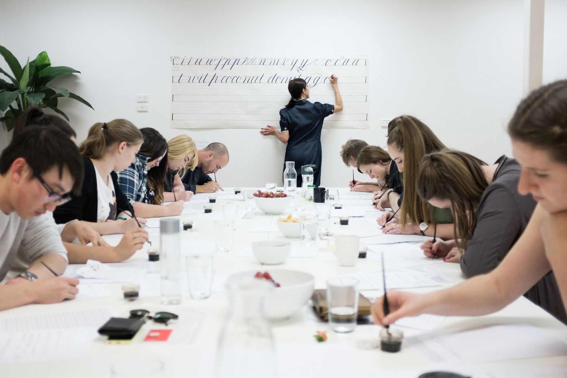 Maria Montes teaching a calligraphy class to many engaged design students.