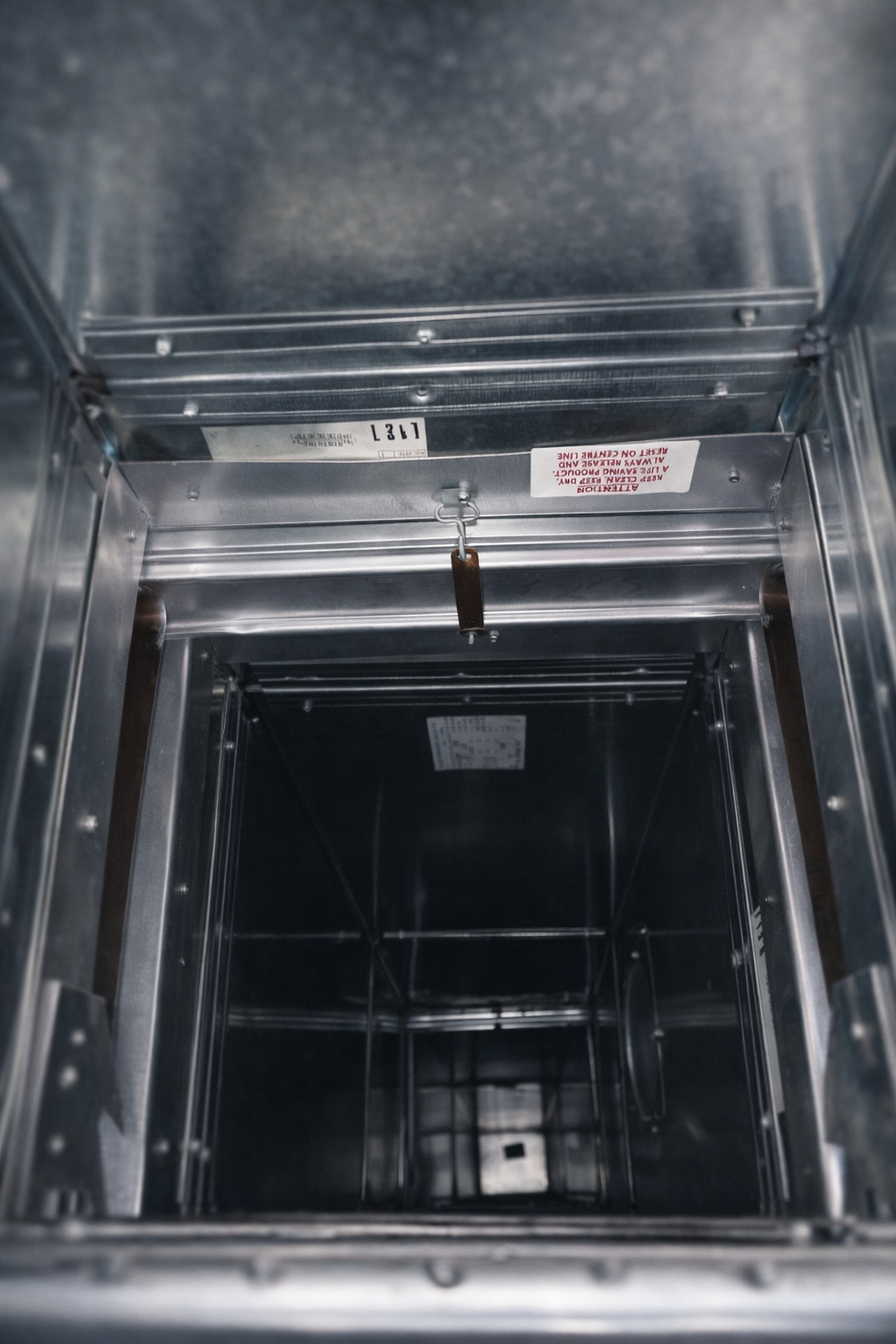 Looking down into a rectangular, metallic shaft, possibly a service or utility access.