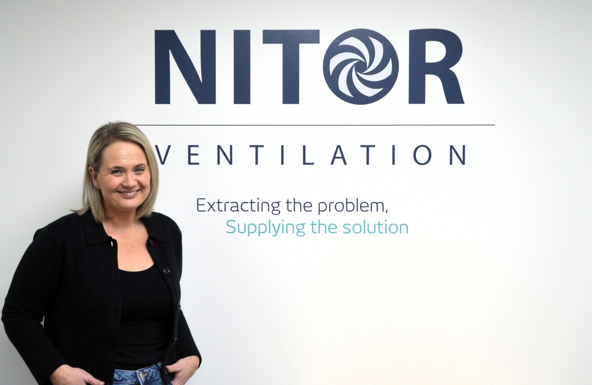 Woman stands in front of a wall with the 