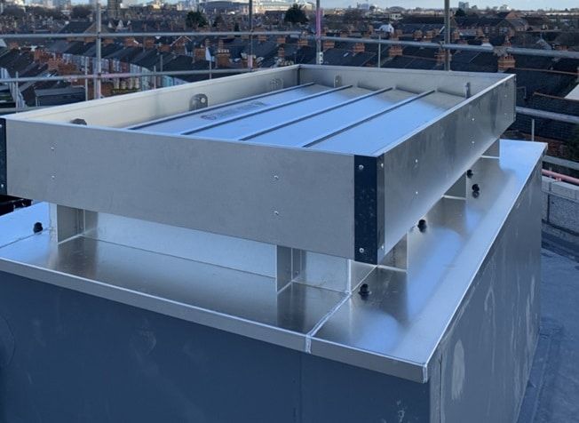 Galvanized steel HVAC ductwork installed on a concrete ceiling in a modern building.