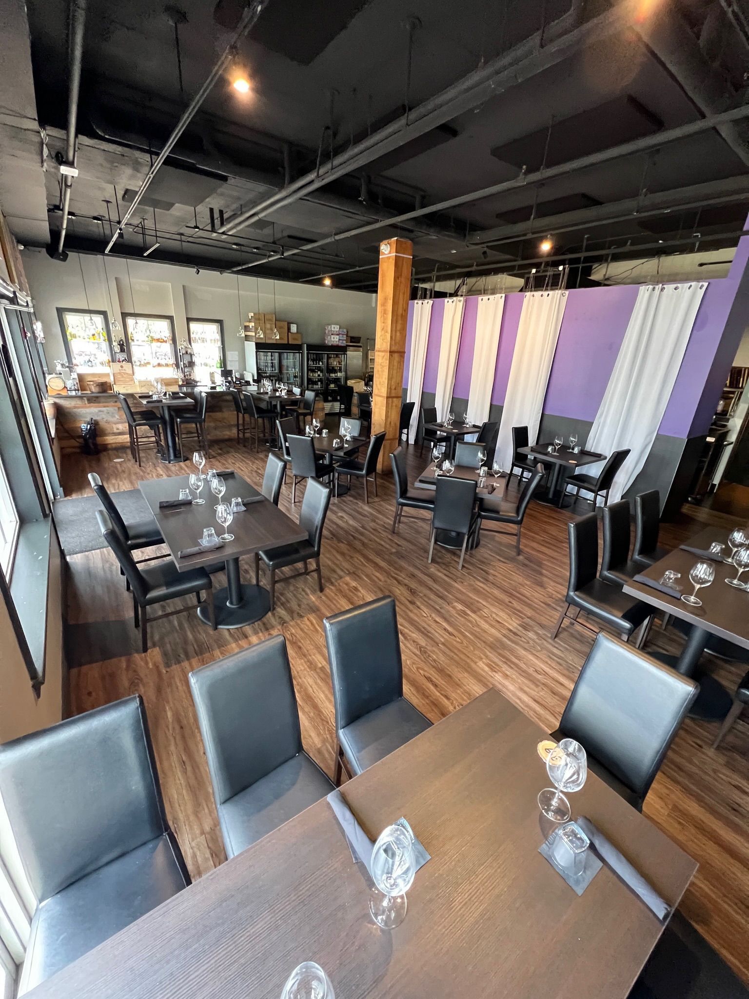 A restaurant with tables and chairs and a barrel in the middle of the room.