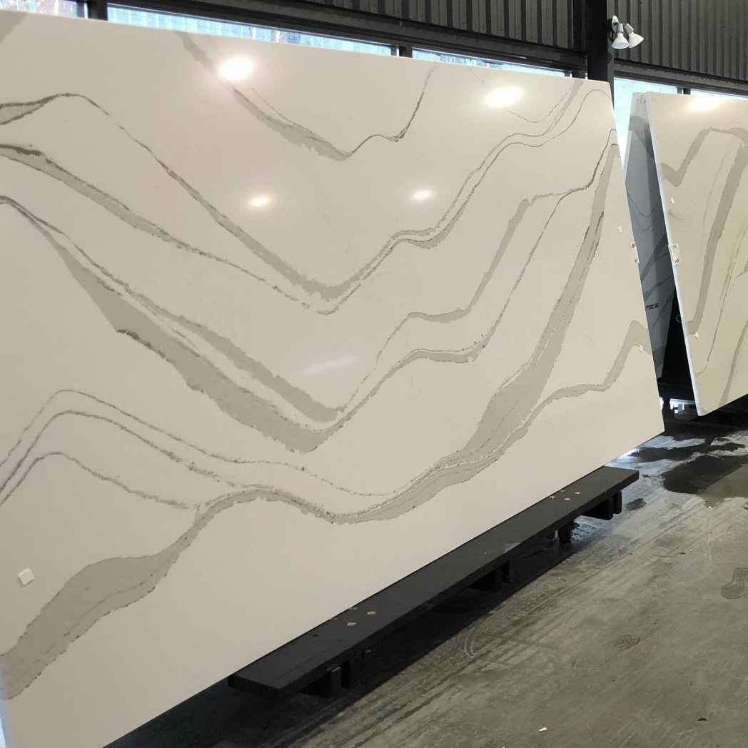 A row of white marble slabs sitting on top of a concrete floor in a showroom.