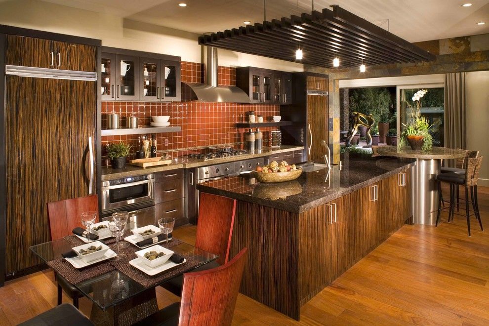 Modern kitchen with wood cabinetry, stainless steel appliances, island with seating, and dining table.