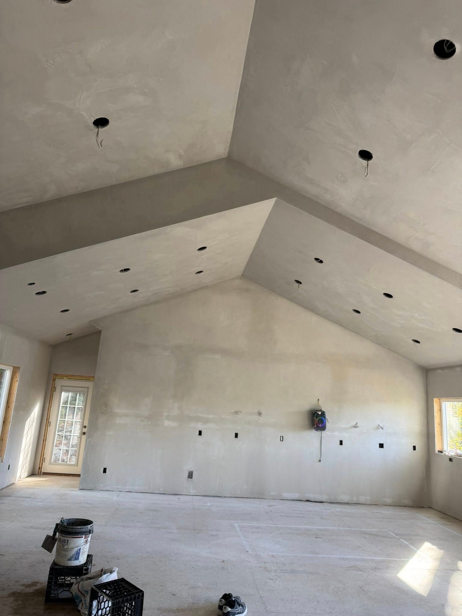 Large, light-colored room with unfinished walls and ceiling. Electrical outlets and recessed lights are visible. Large, light-colored room with unfinished walls and ceiling. Electrical outlets and recessed lights are visible.