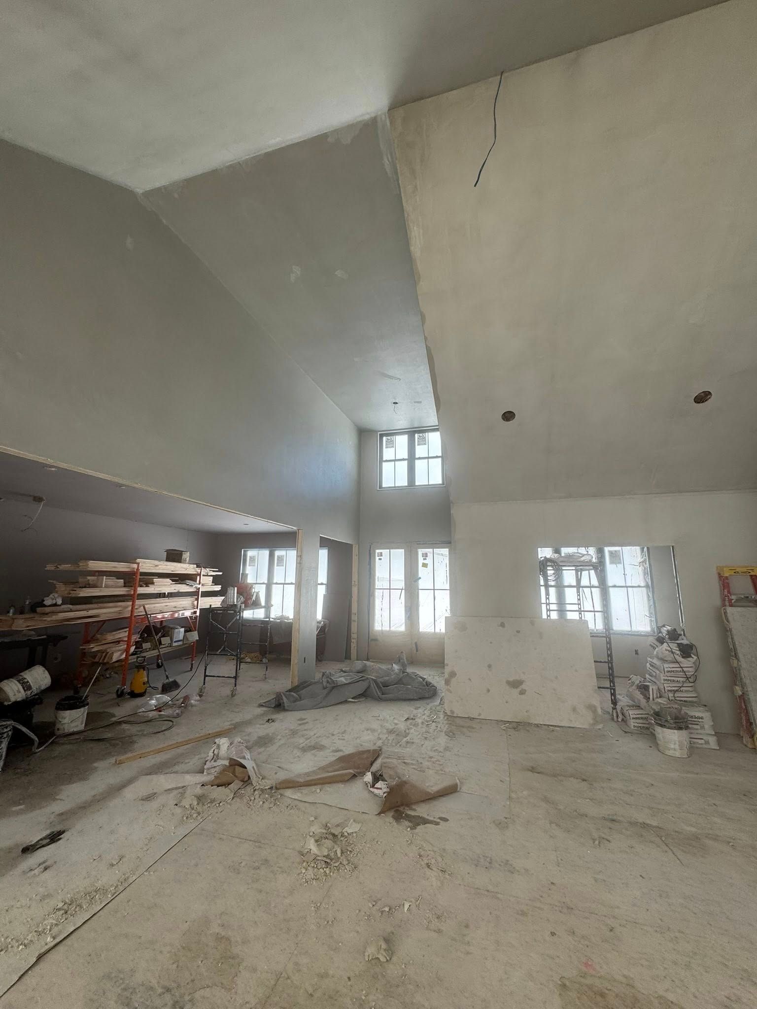 Interior of a room under construction, with high ceilings, unfinished walls, and scattered materials. Interior of a room under construction, with high ceilings, unfinished walls, and scattered materials.