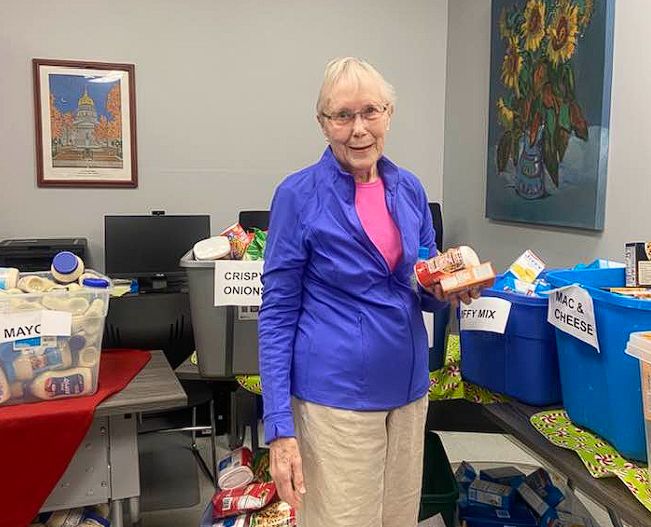 Woman standing in a room beside donation bins filled with assorted items.