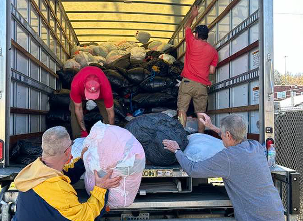 Volunteers loading bags into a truck, with others passing them from the ground.