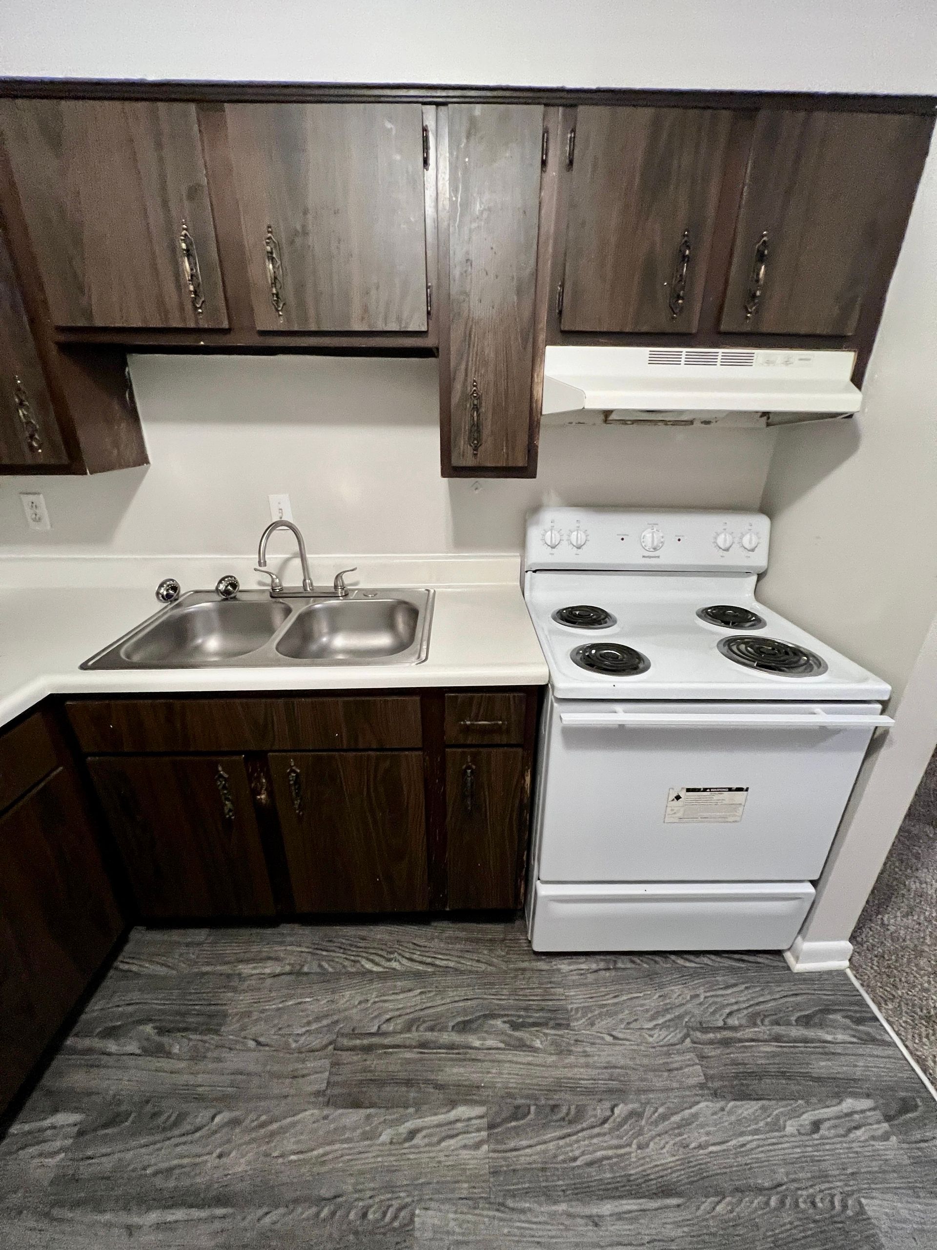 A kitchen with a stove , sink , and cabinets.