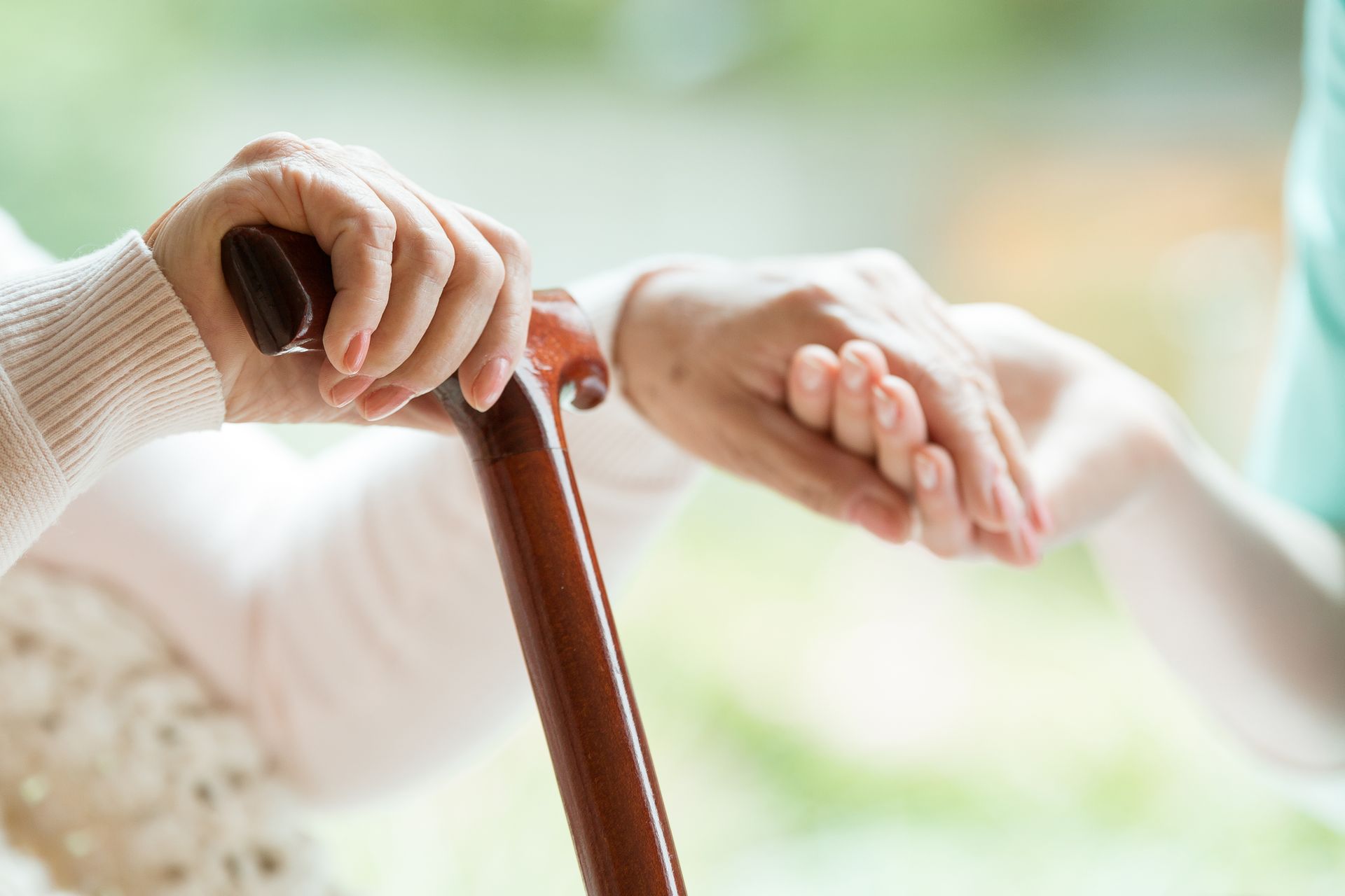 A woman is helping an elderly woman with a cane.