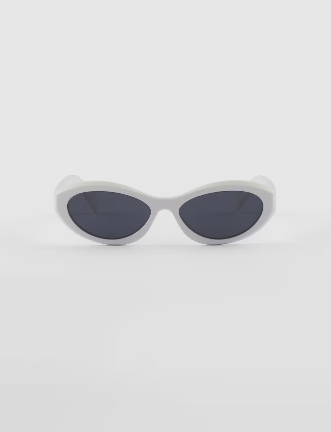 A pair of white sunglasses with black lenses on a white surface.