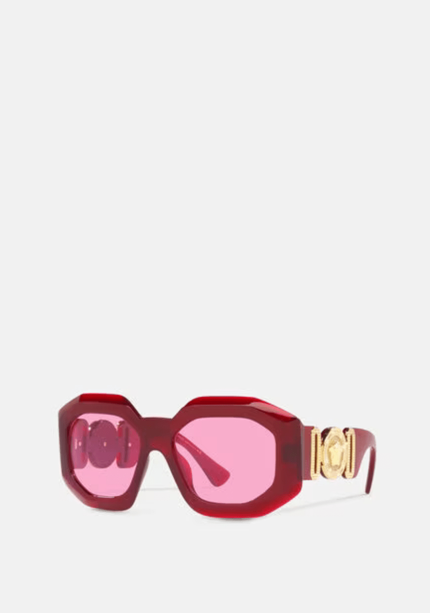 A pair of red sunglasses with pink lenses on a white background.