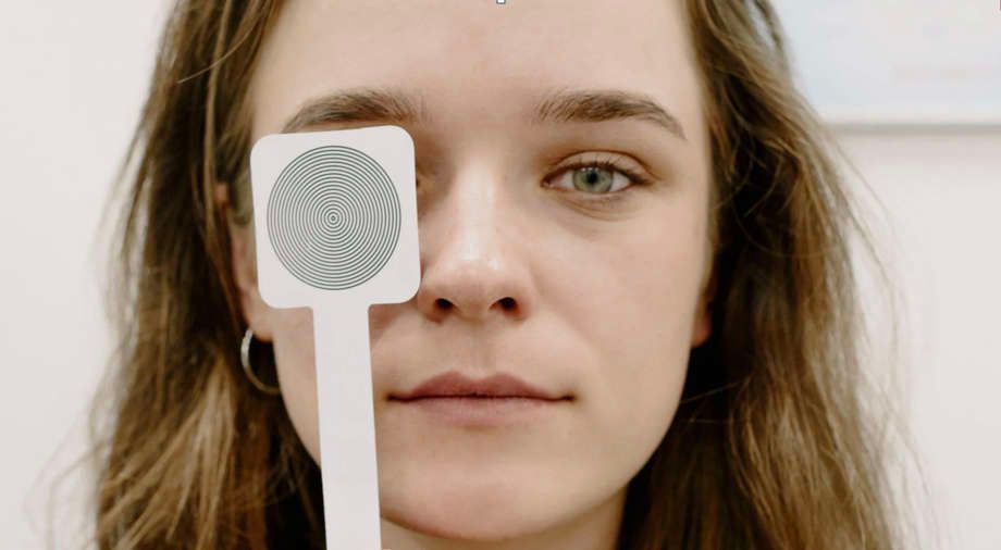 A woman is holding a card in front of her eye.