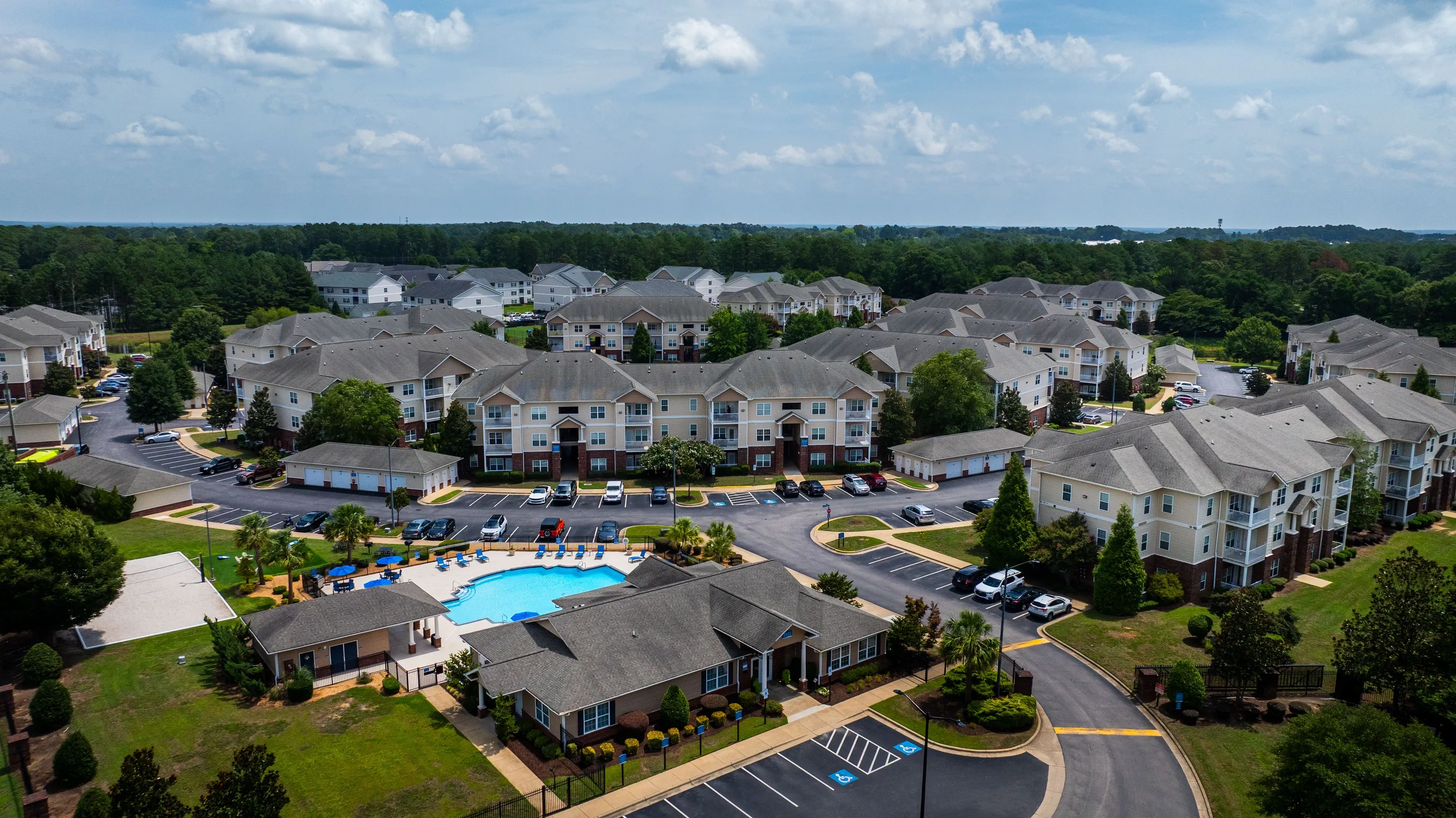 Aerial view of apartment complex with pool and surrounding buildings