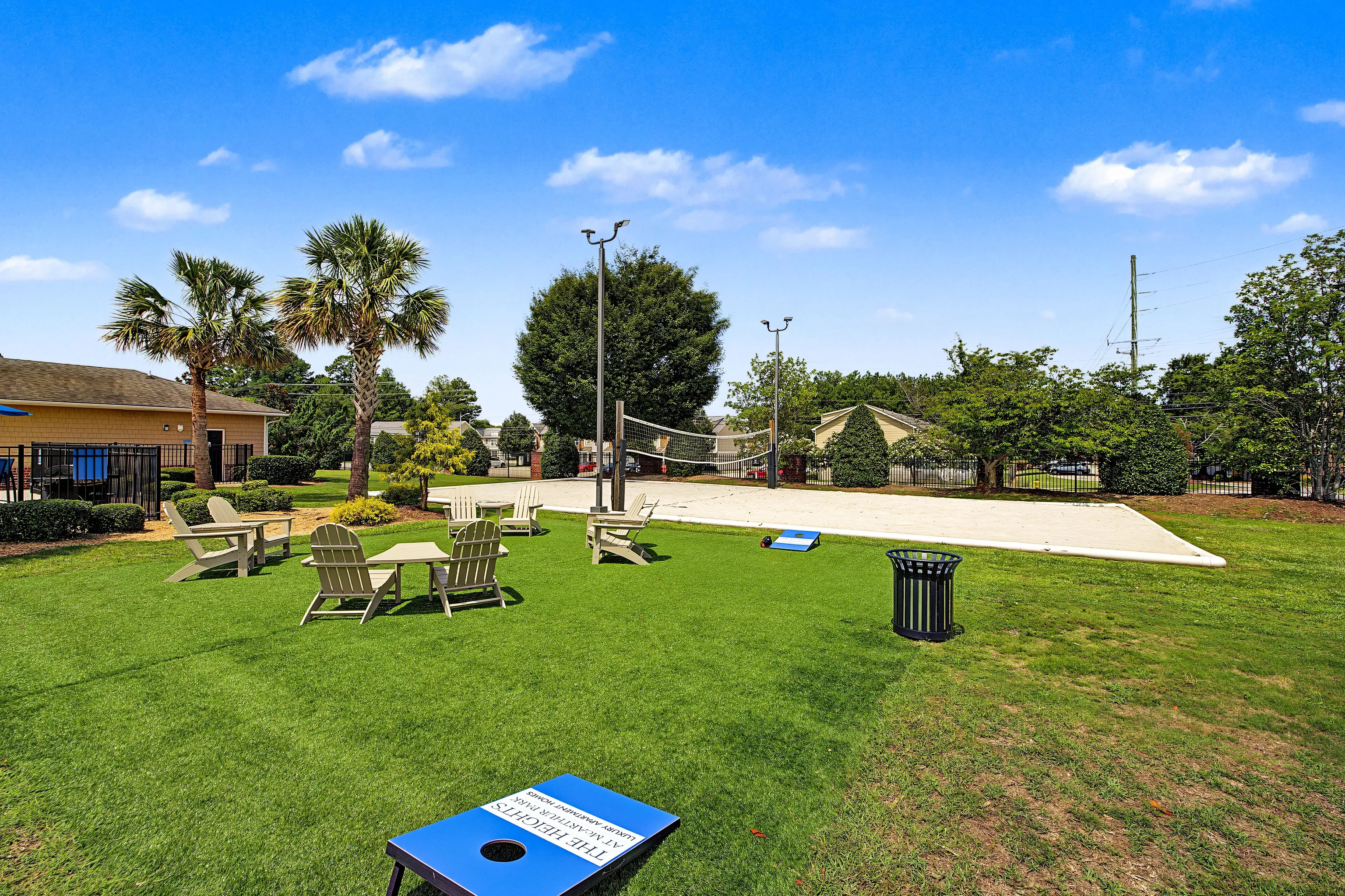 Community volleyball court with seating areas and cornhole game.