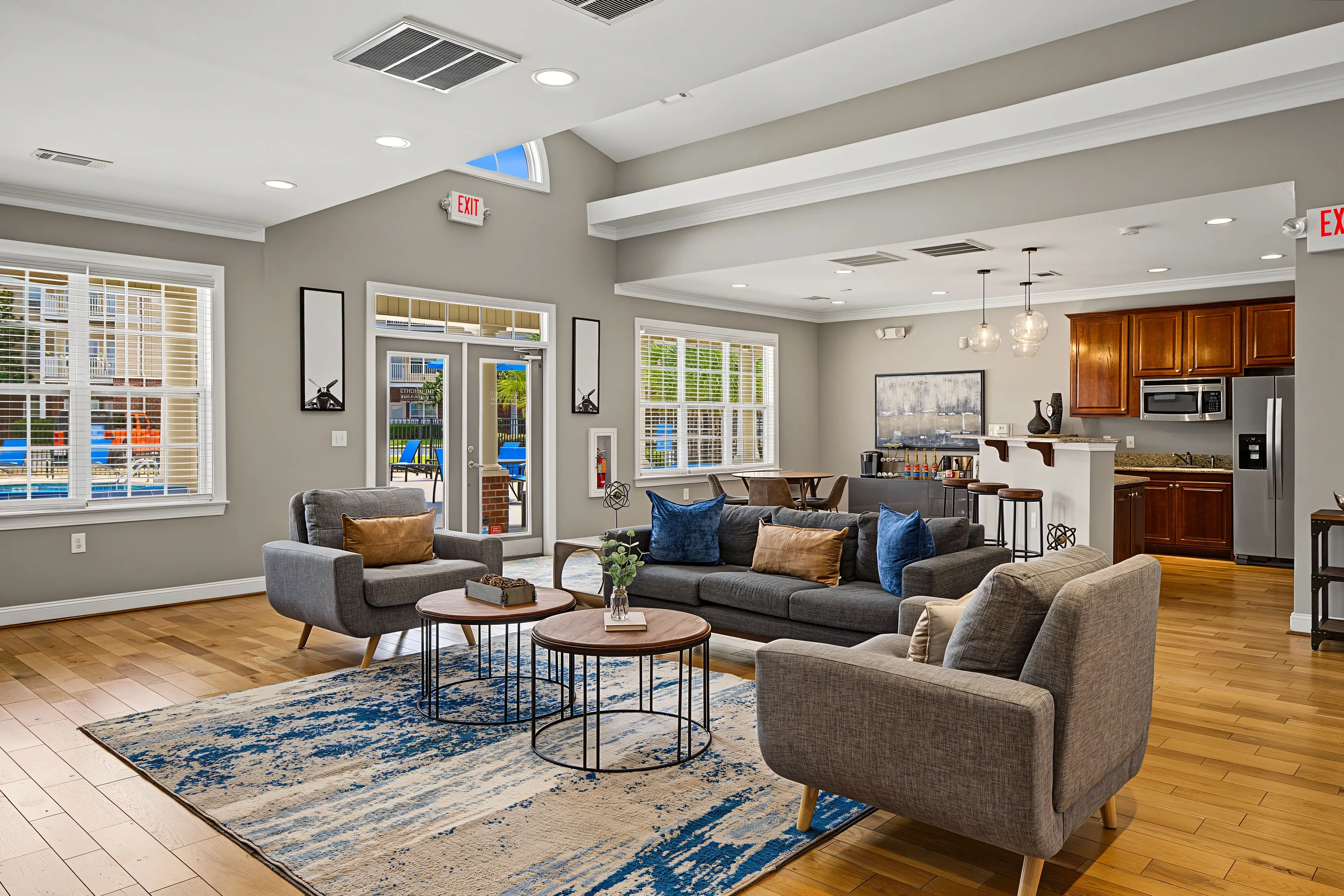 Community lounge area with seating, a kitchen, and a view of the pool.