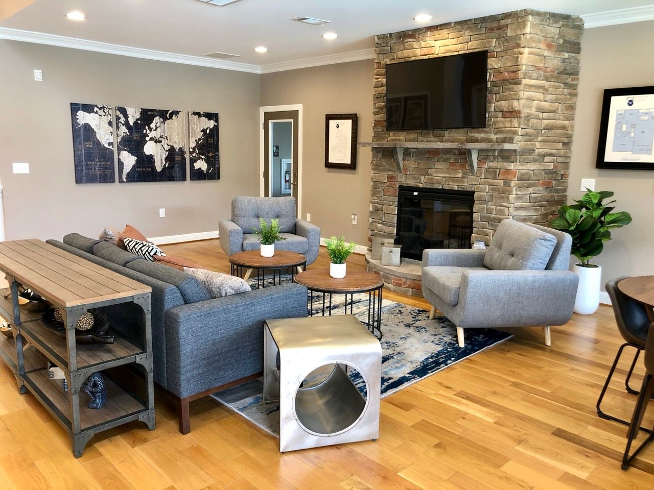 Community lounge with stone fireplace, gray seating, and coffee tables.
