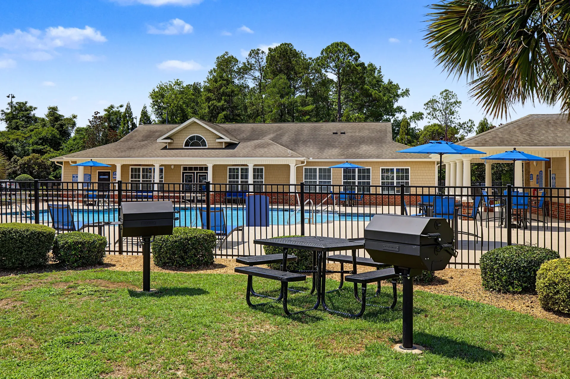 Outdoor swimming pool with lounge chairs and picnic tables with grills.