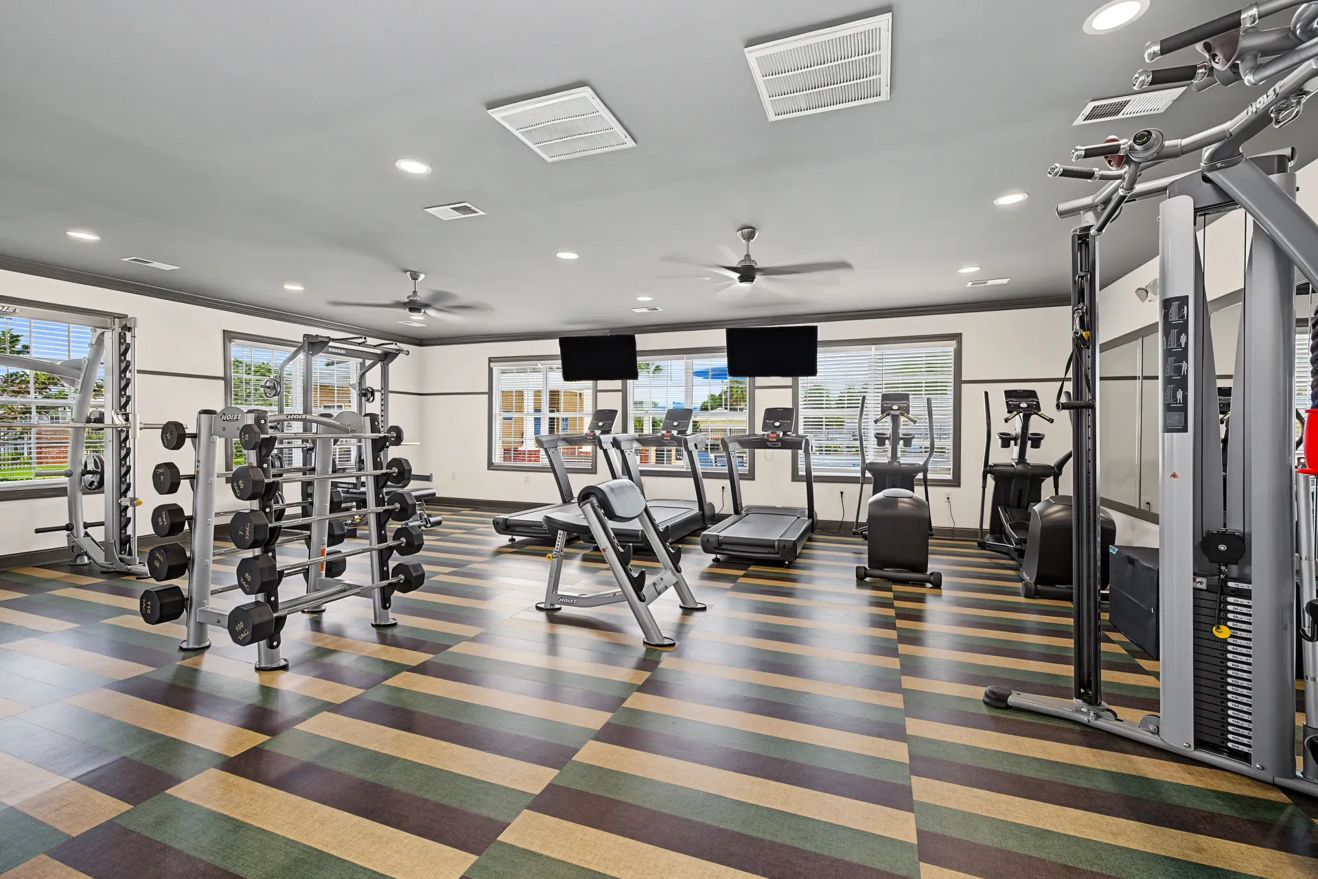 Fitness center with treadmills, ellipticals, weight racks, and a cable machine.