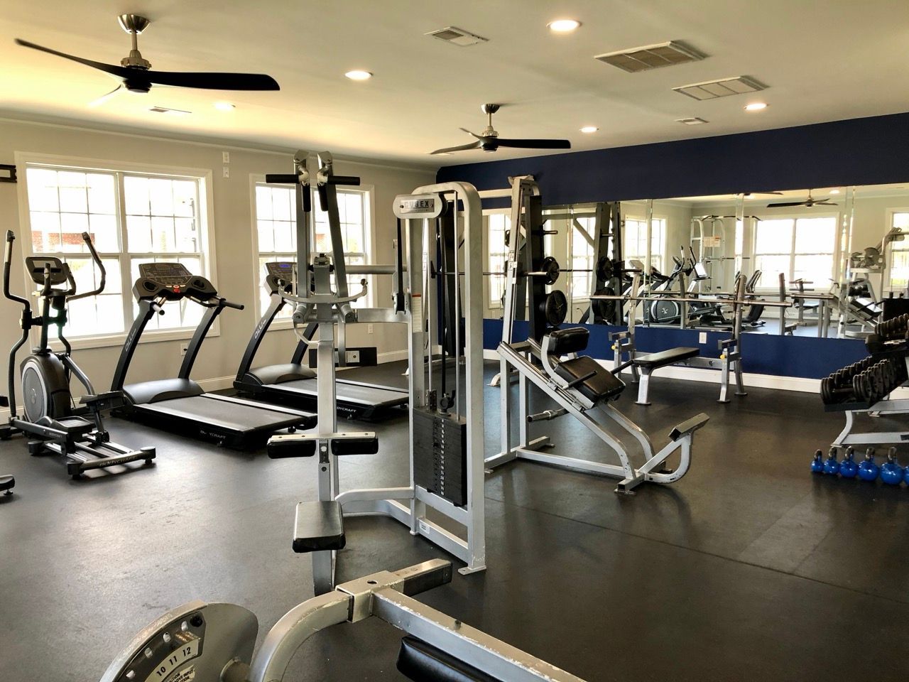 Fitness center with treadmills, weight machines, benches, and mirrors