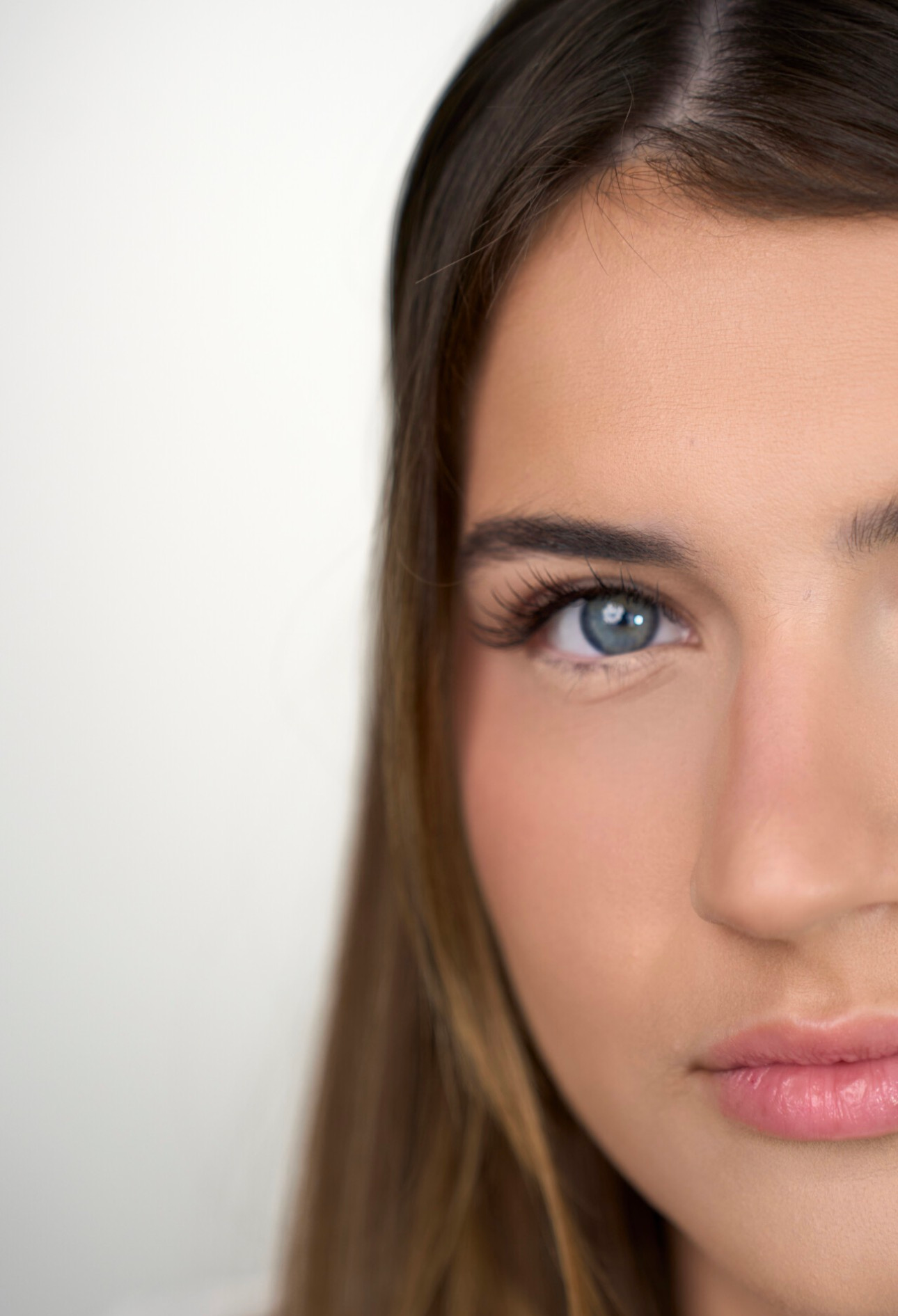 Close-up of a face with blue eyes and natural makeup against a white background