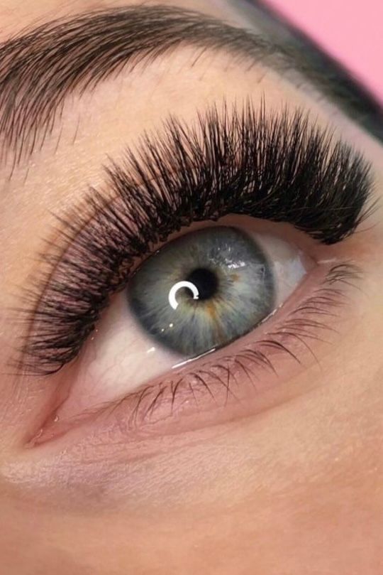 A close up of a woman 's eye with long eyelashes.