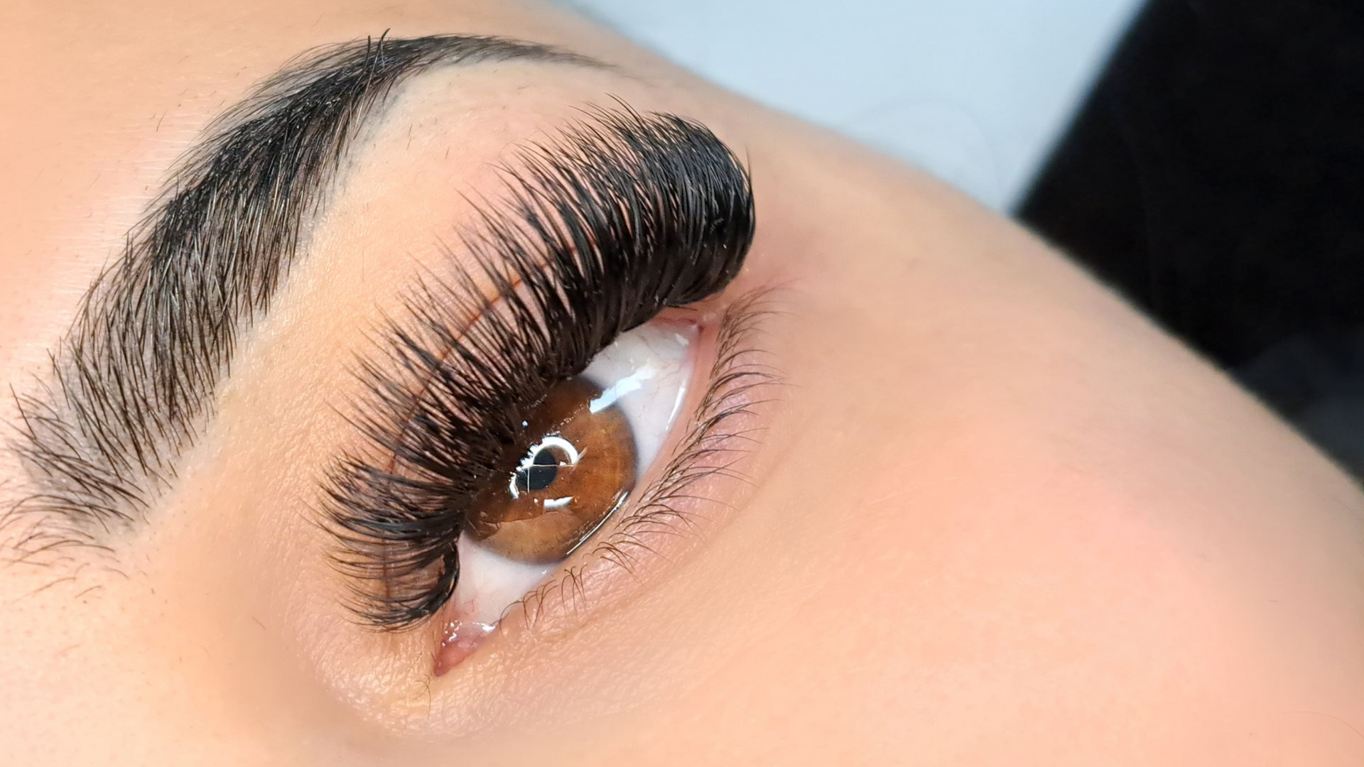 Close-up of an eye with long, thick black eyelashes and a brown iris