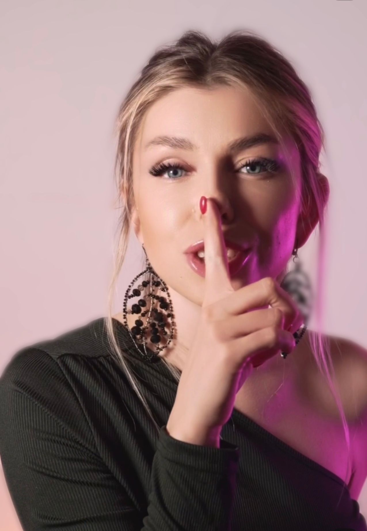 A woman is holding her finger to her mouth.