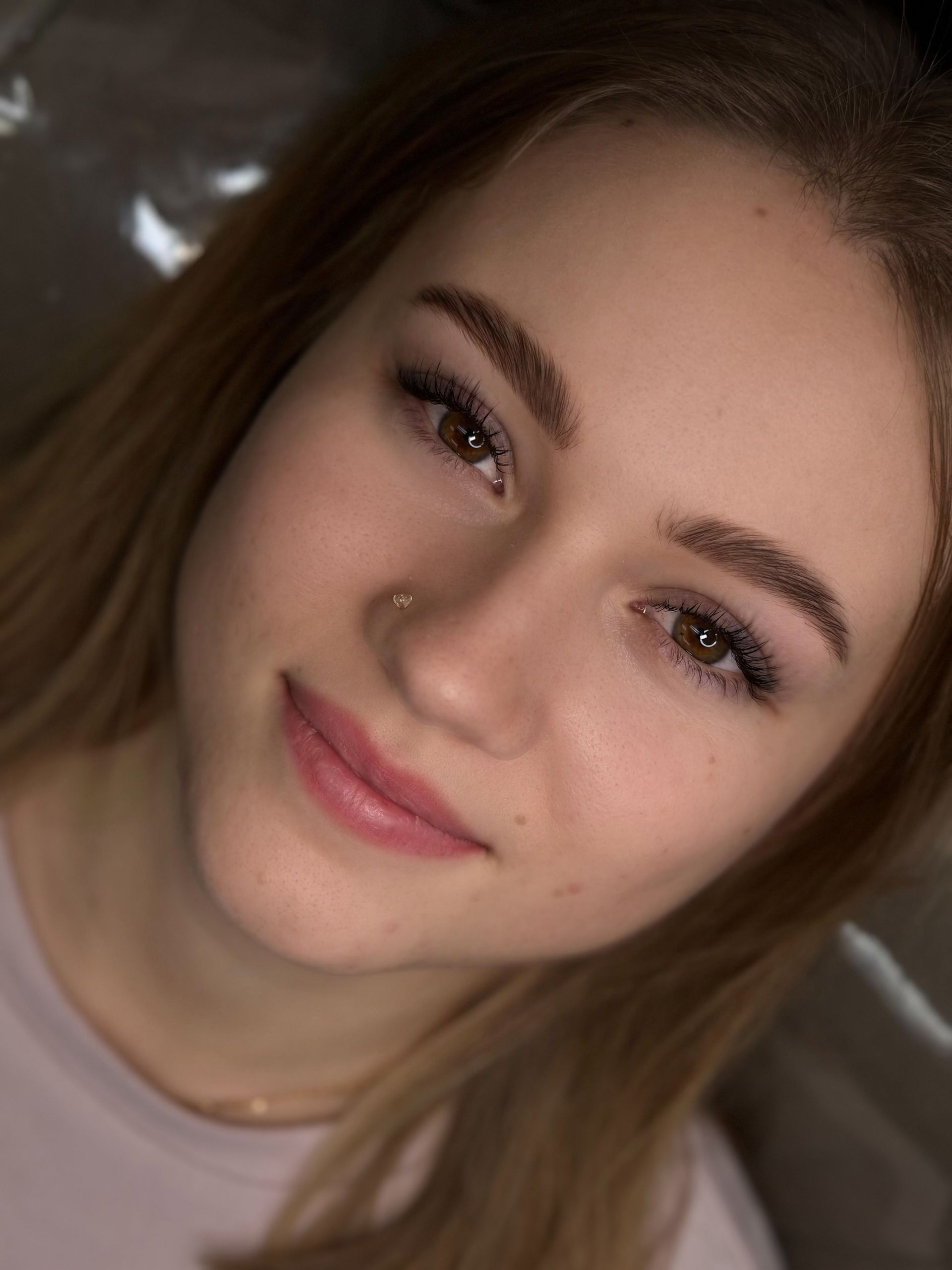 A close up of a young woman 's face with a nose ring.