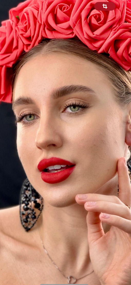 A woman wearing a red flower crown and red lipstick.