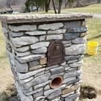 A stone pillar with a mailbox in the middle of it.