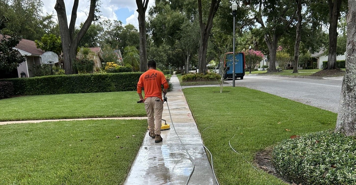 A man is using a pressure washer Surface Cleaner to clean a sidewalk.
