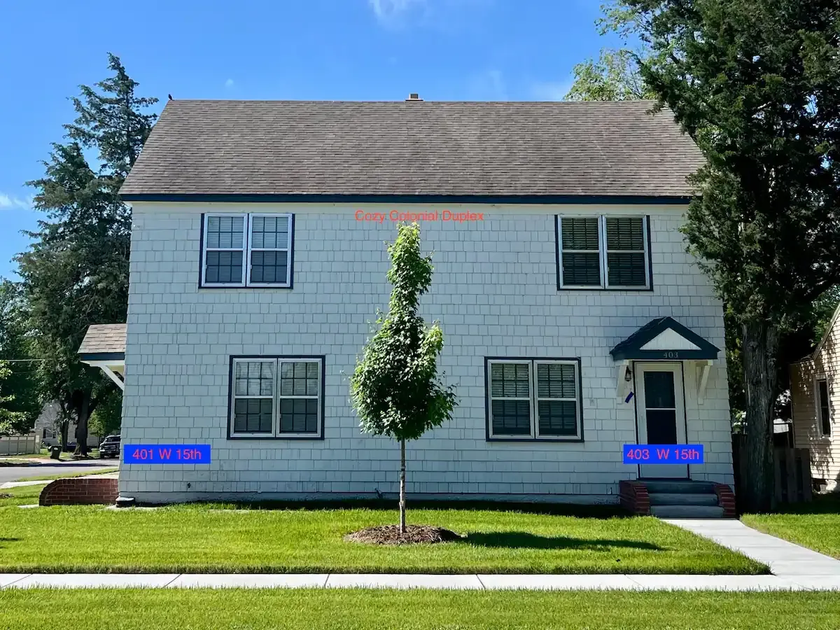 A white 2-story house with a tree in front of it