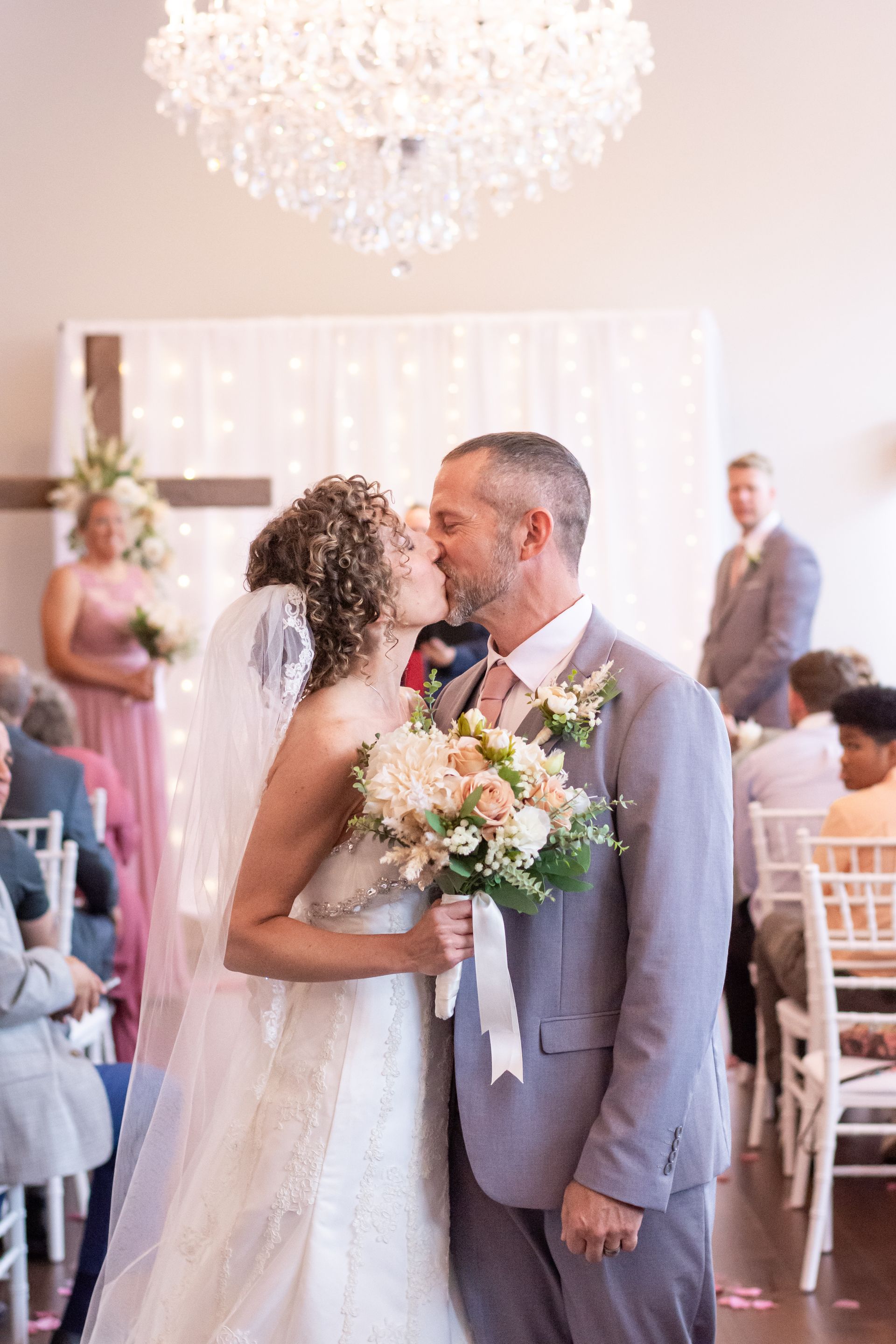 A bride and groom kissing at their wedding ceremony in front of their wedding guests.
