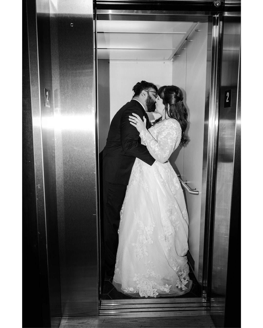 A bride and groom are kissing in an elevator.