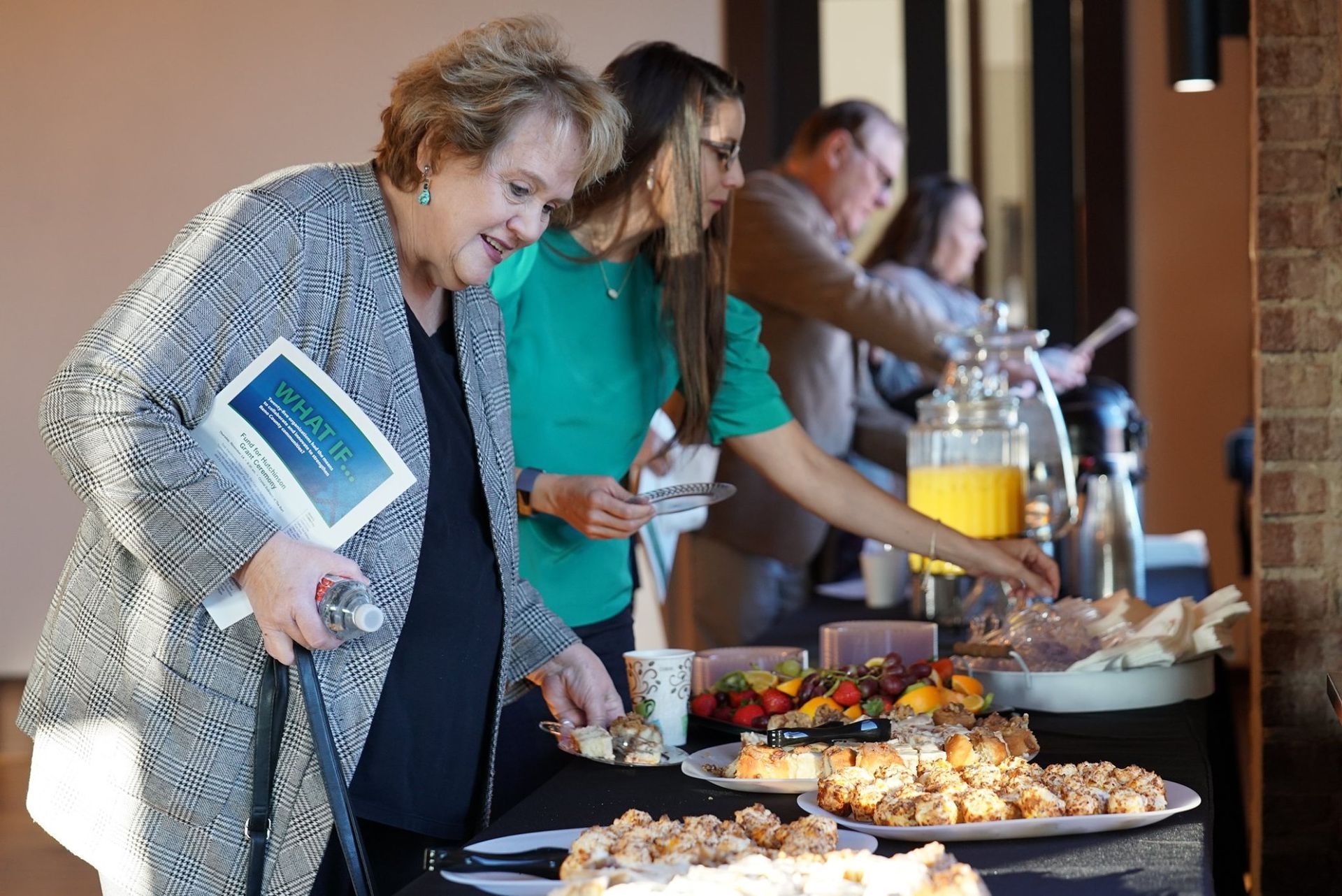 A group of people are standing around a table getting food.