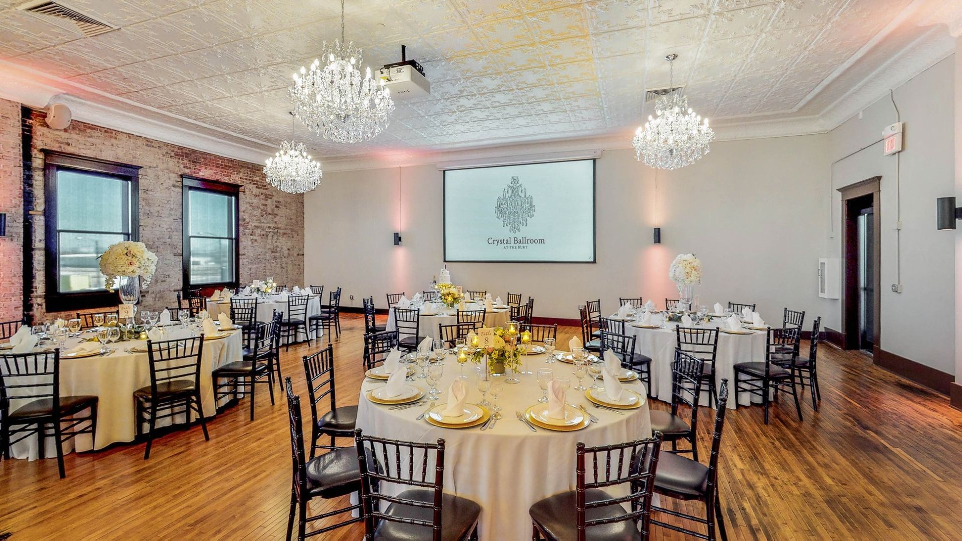 A large room with tables and chairs set up for a wedding reception.
