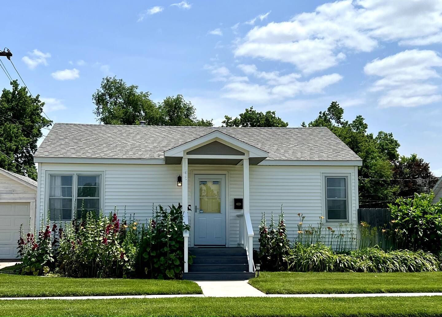 A small white house with a porch and stairs