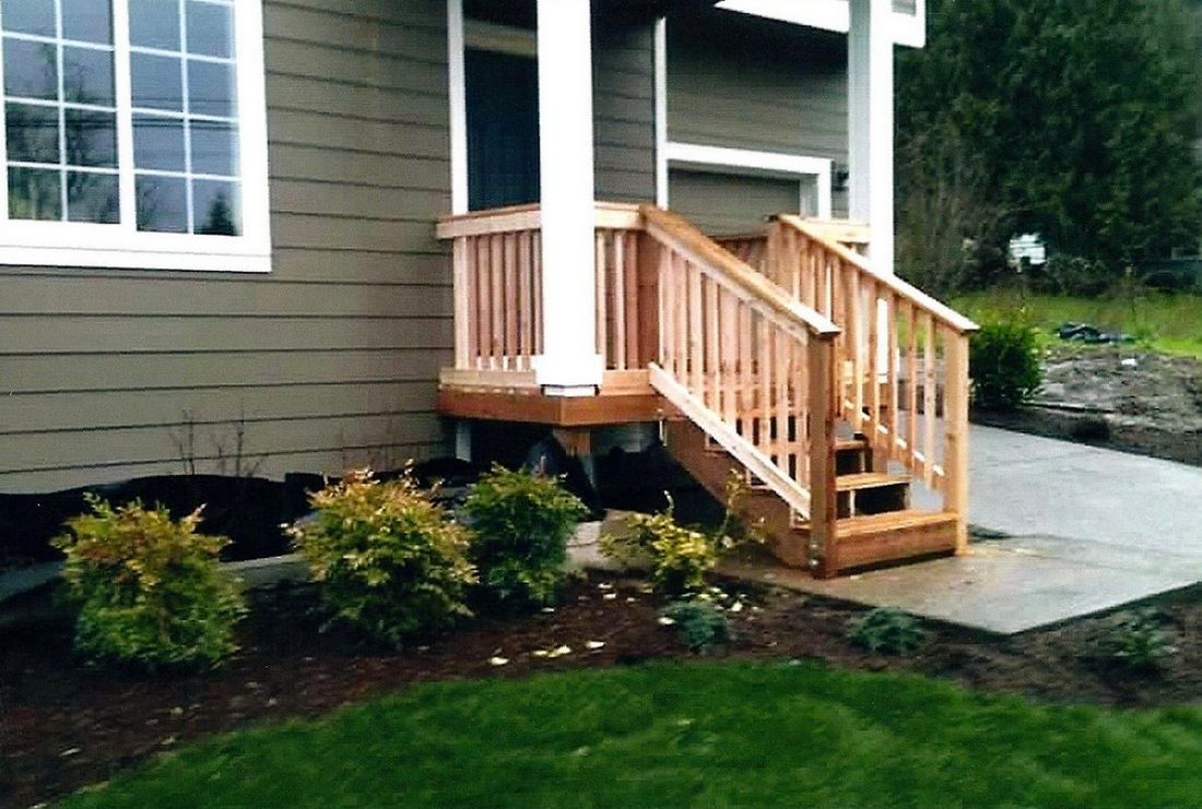 Brown house exterior with wooden steps and railing leading to a small porch.