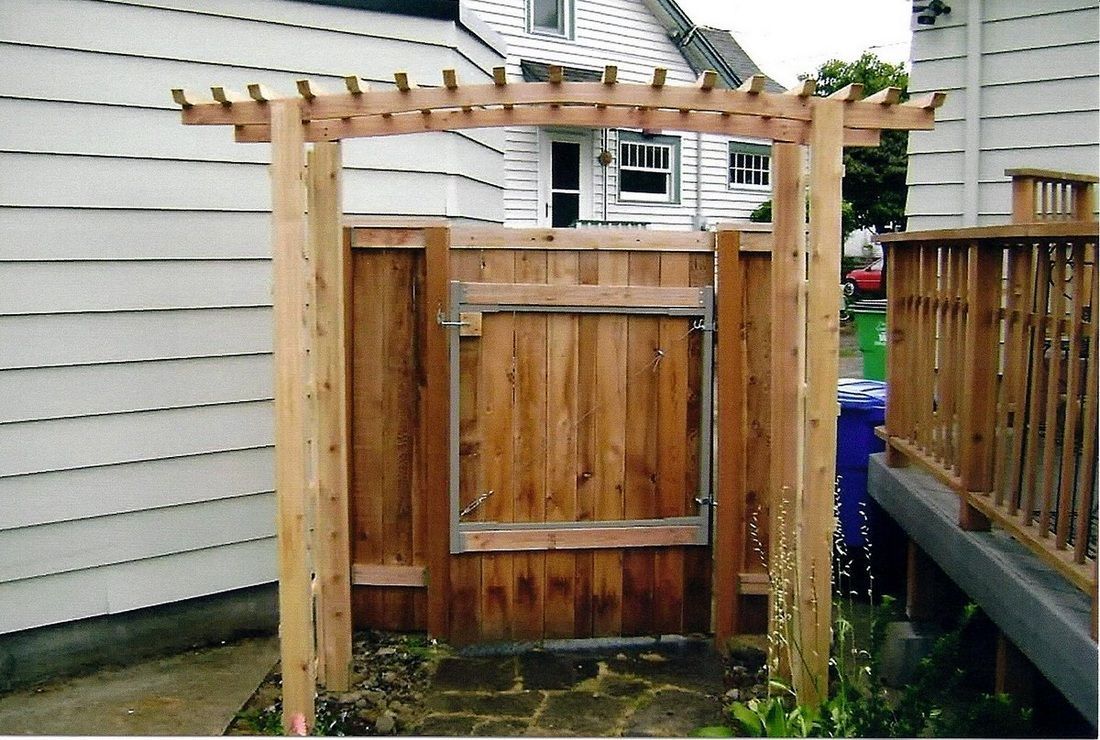 Wooden gate with pergola entrance in a backyard.