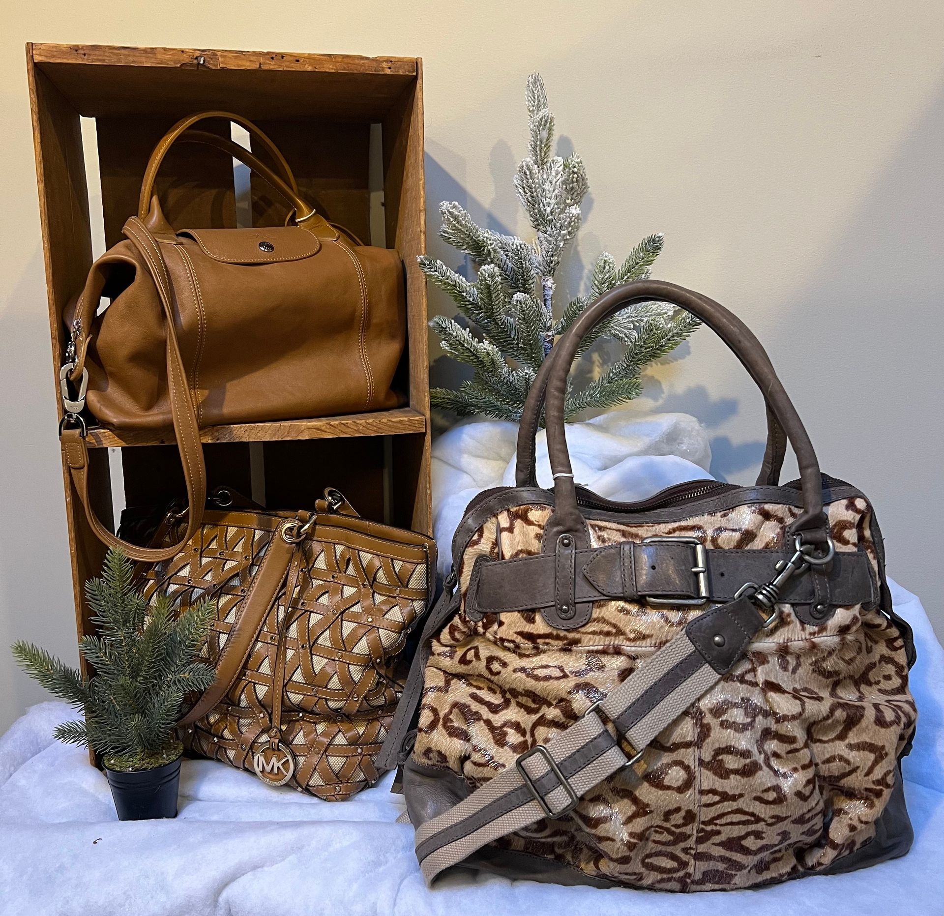 A leopard print bag sits on a table next to other bags