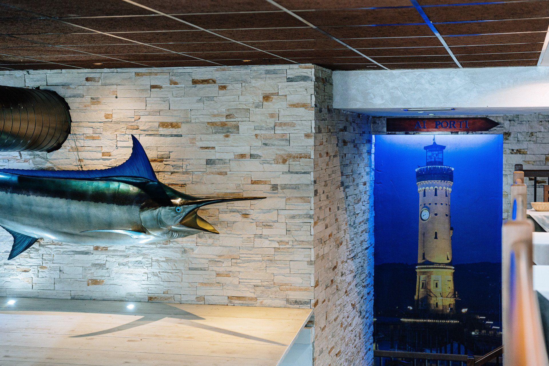 Un marlin imbalsamato e una scena con un faro in un interno con accenti in mattoni e pietra.
