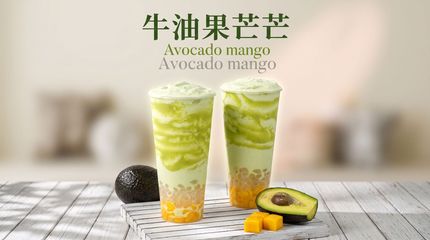 Two avocado mango drinks in clear cups on a table, with avocados and mango pieces beside them.