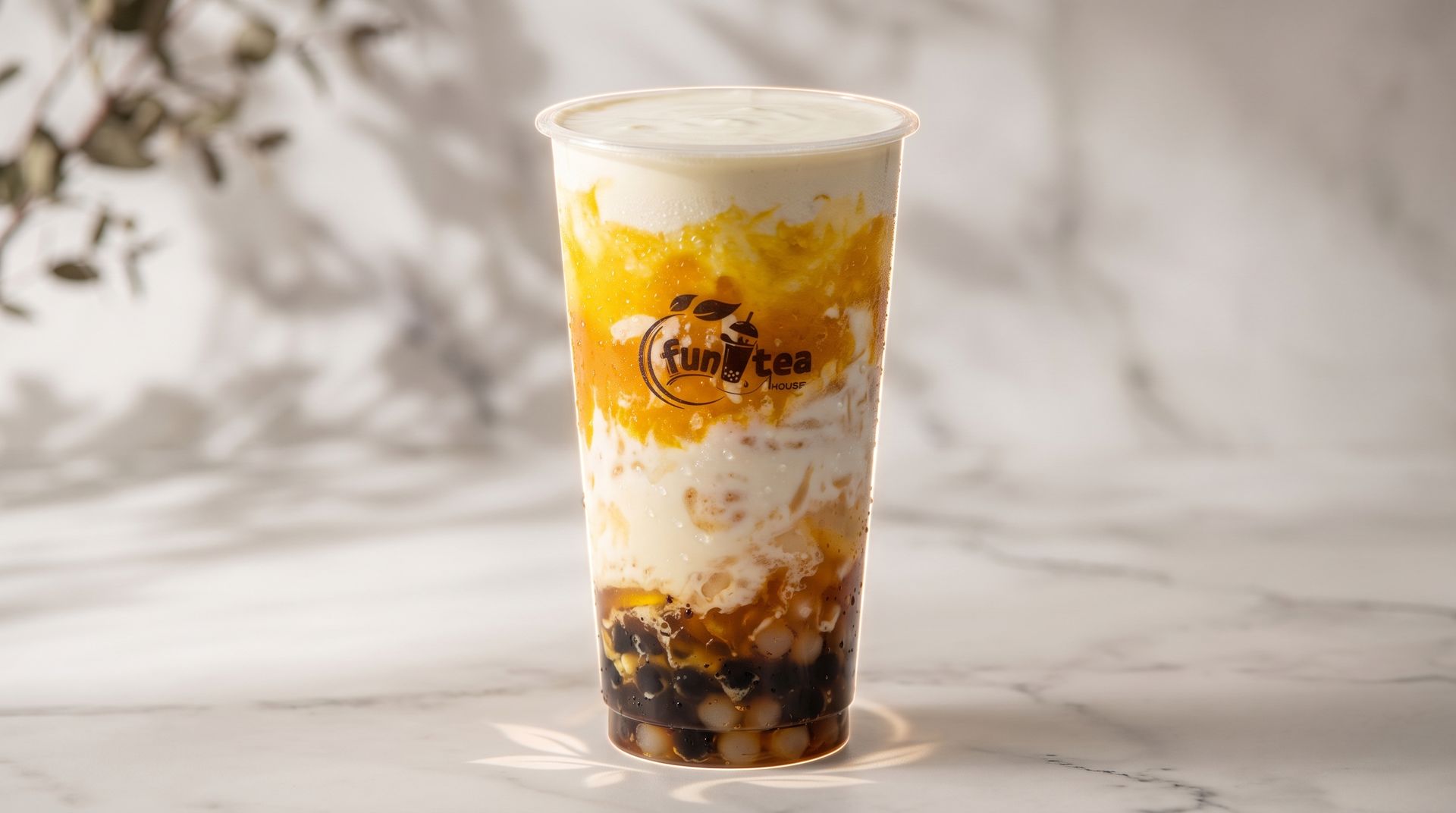 Layered iced drink in a clear cup with white cream, yellow fruit, and dark tapioca pearls on a light surface
