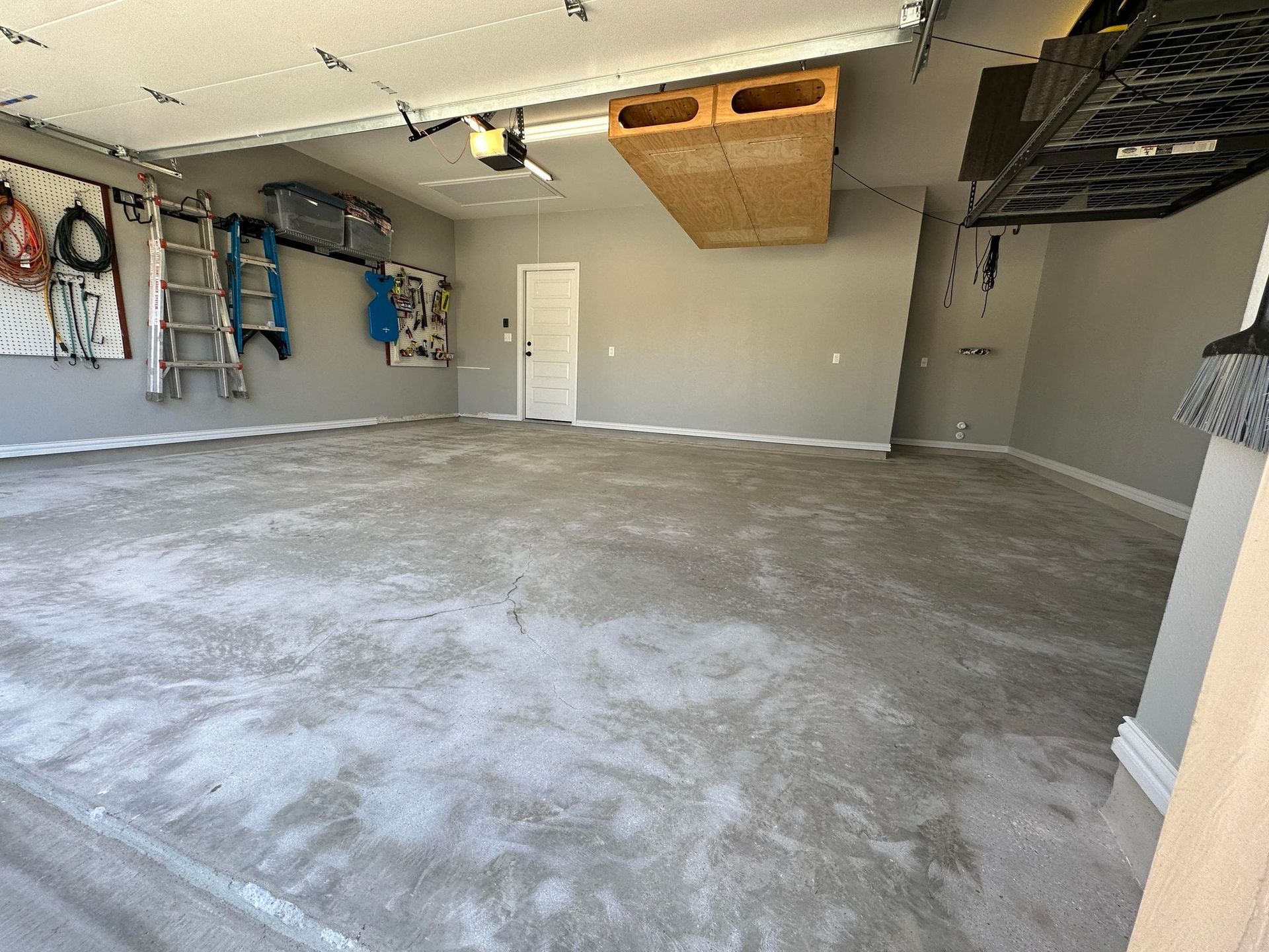 an empty garage with a concrete floor and a ladder hanging from the ceiling .