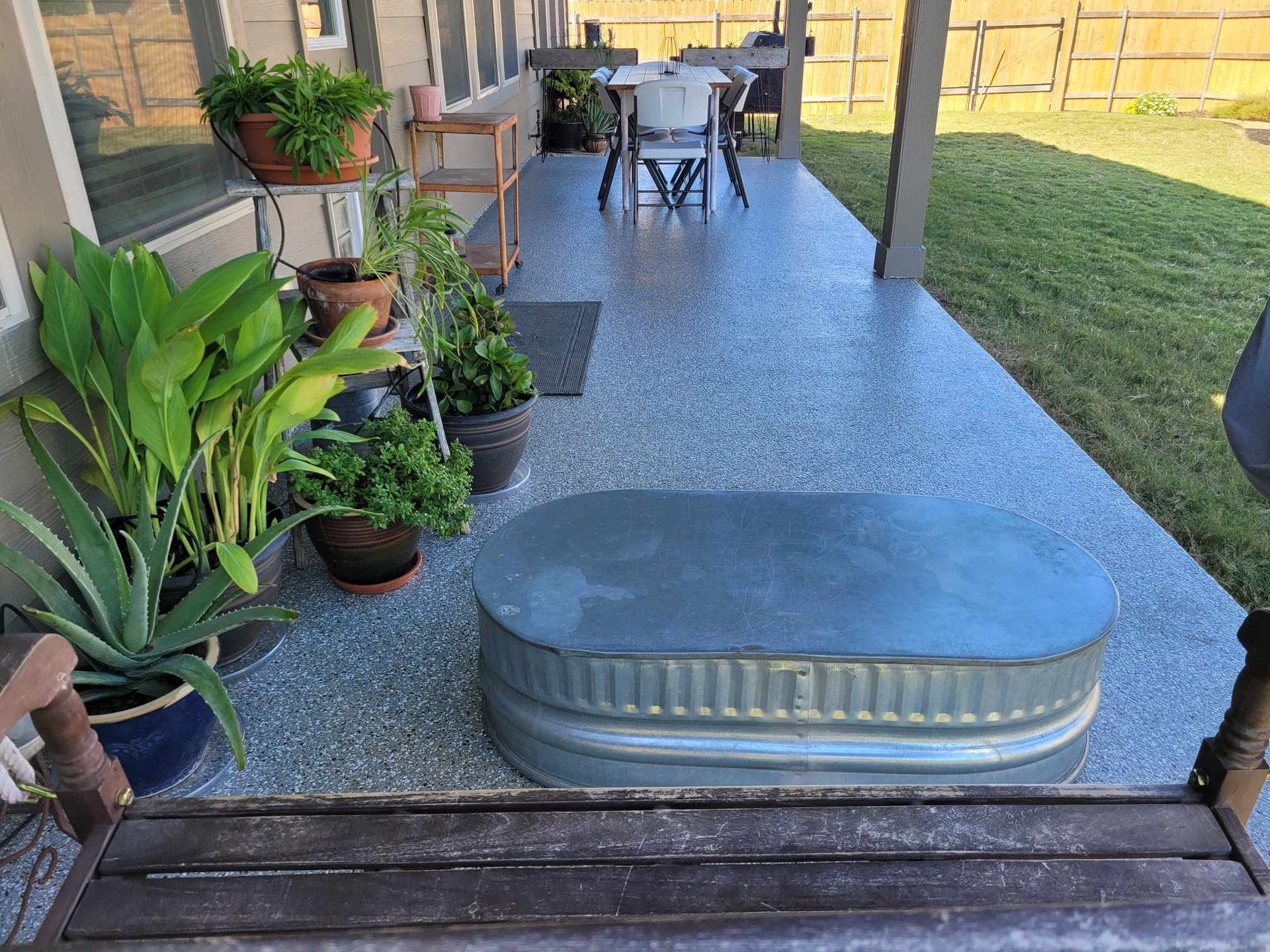 a metal trough is sitting on a porch next to a table and chairs with new polyasprtic floor coating.