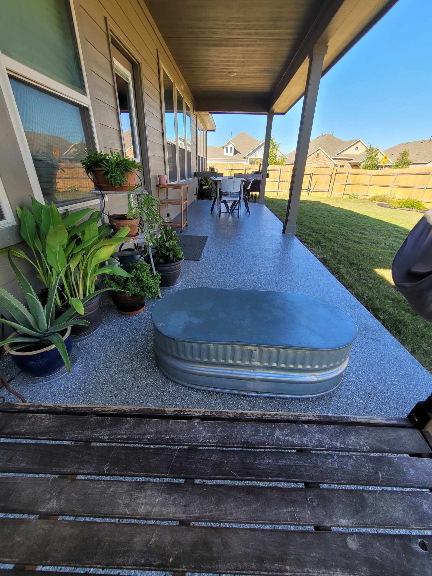 A porch with epoxy coating and a table and chairs and plants on it.